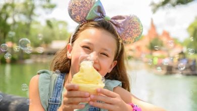 kid wearing mickey ears holding dole whip in disney world