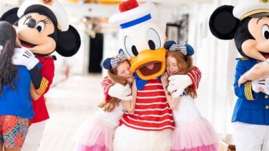 Three children hug Disney characters Minnie Mouse, Donald Duck, and Mickey Mouse, who are dressed in nautical costumes on a brightly lit cruise ship deck—a magical moment and the perfect start to an adventure filled with Disney Cruise Tips.