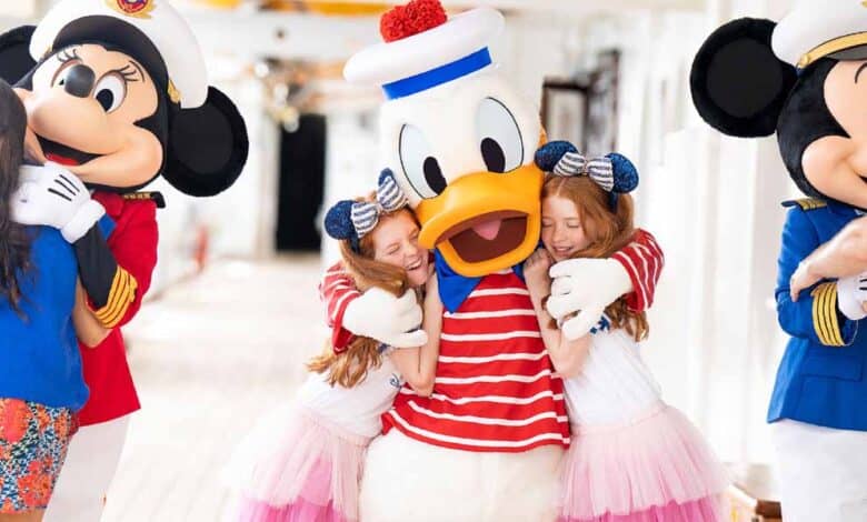 Three children hug Disney characters Minnie Mouse, Donald Duck, and Mickey Mouse, who are dressed in nautical costumes on a brightly lit cruise ship deck—a magical moment and the perfect start to an adventure filled with Disney Cruise Tips.