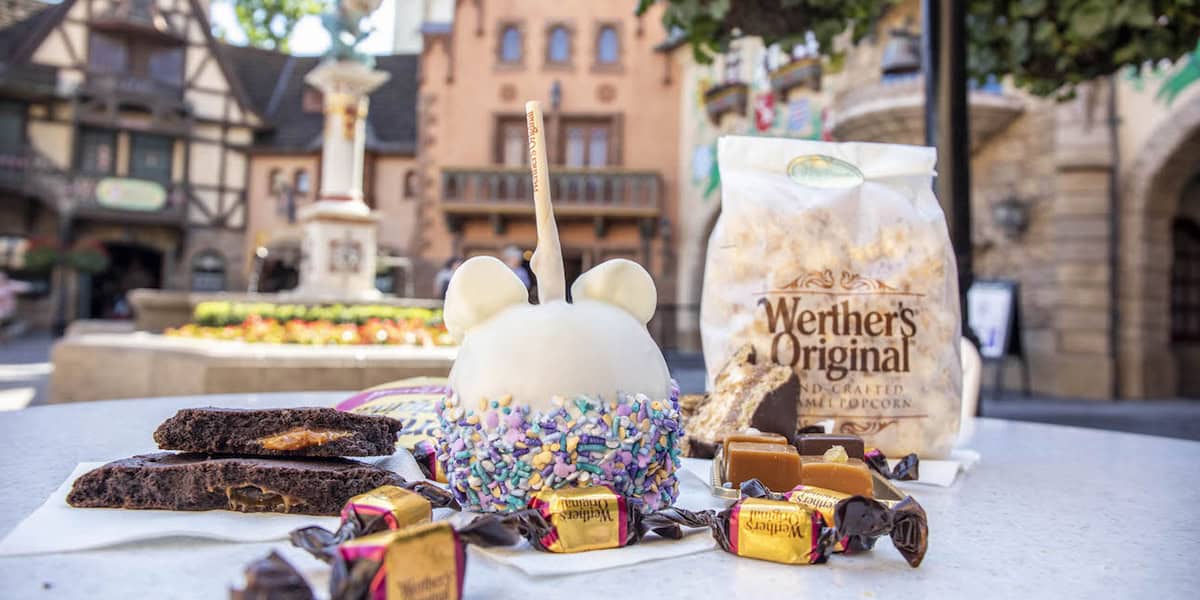 A table displays a white chocolate-covered caramel apple with sprinkles, Werther’s Original caramel popcorn, chocolates, and brownies.