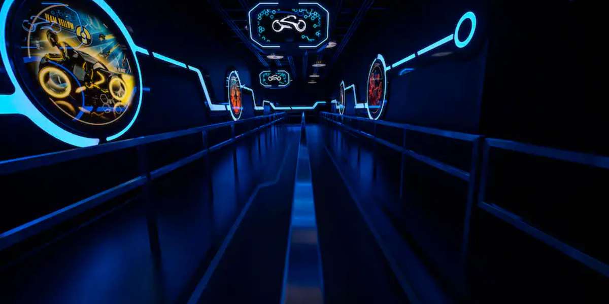 the dark blue ambiance of the tron queue, with guest barriers of metal and images featuring futuristic teams yellow and red in blue lled frames