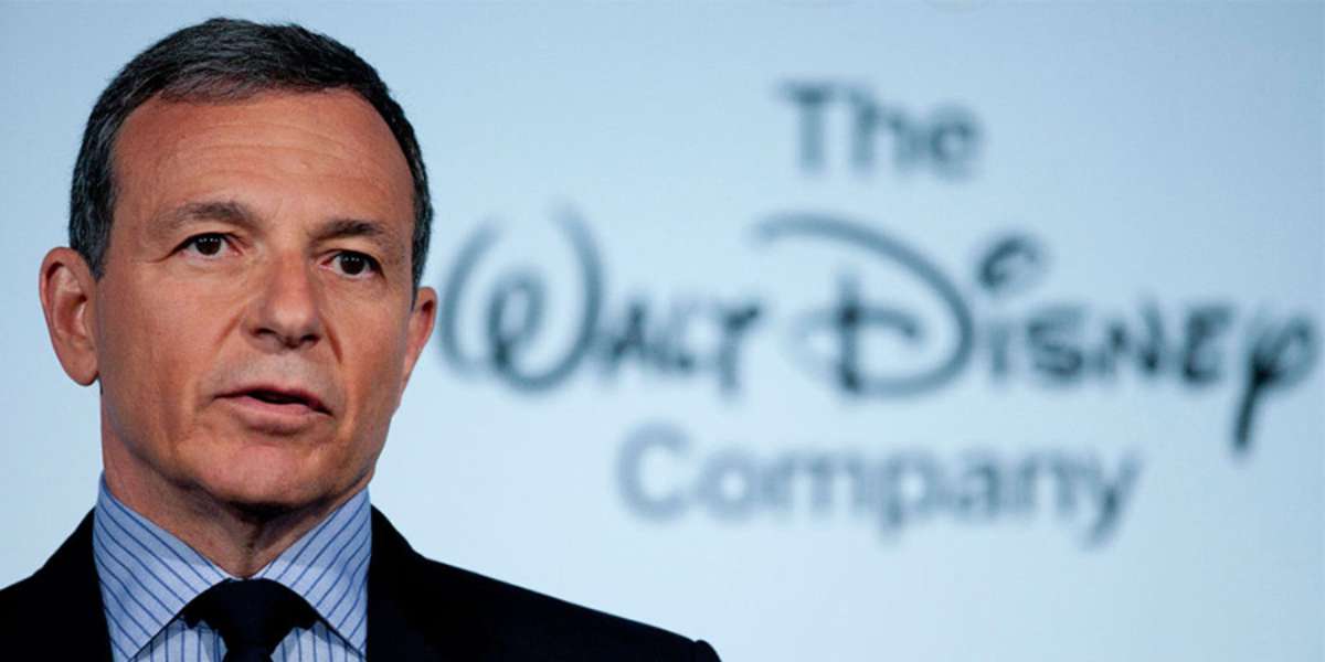 disney ceo bob iger in a black suite before a white background and walt disney company logo
