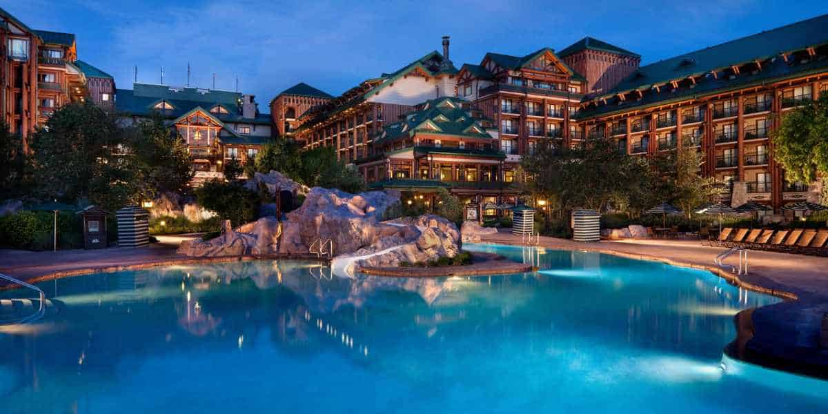 A Disney World hotel during the evening hours with a pool in the front and Disney guests staying inside.