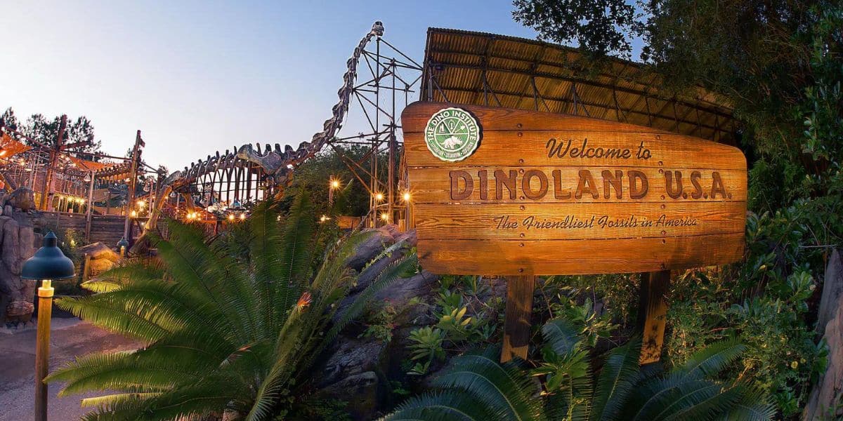 The entrance sign to Dinoland inside of Disney World on a sunny evening as teh sun sets on the left.