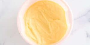 A top view of a bowl of smooth, yellow Dole Whip on a white marble surface.