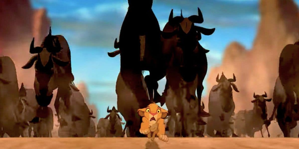 Young lion cub looking scared as a herd of wildebeests stampedes towards him in a dusty savannah scene. Simba The Lion King