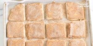 A tray of freshly baked cinnamon rolls covered in sugar, displayed on a parchment-lined baking sheet, with the watermark "favorite family recipes" visible.