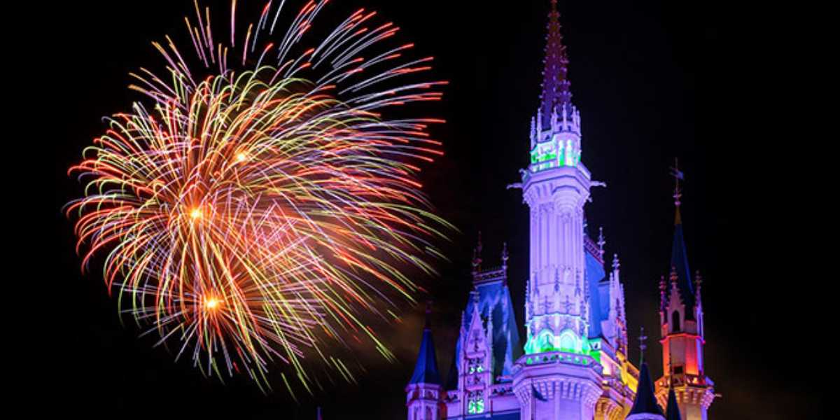 Fireworks burst in colorful displays above a brightly lit castle at night, creating a vibrant and magical atmosphere.