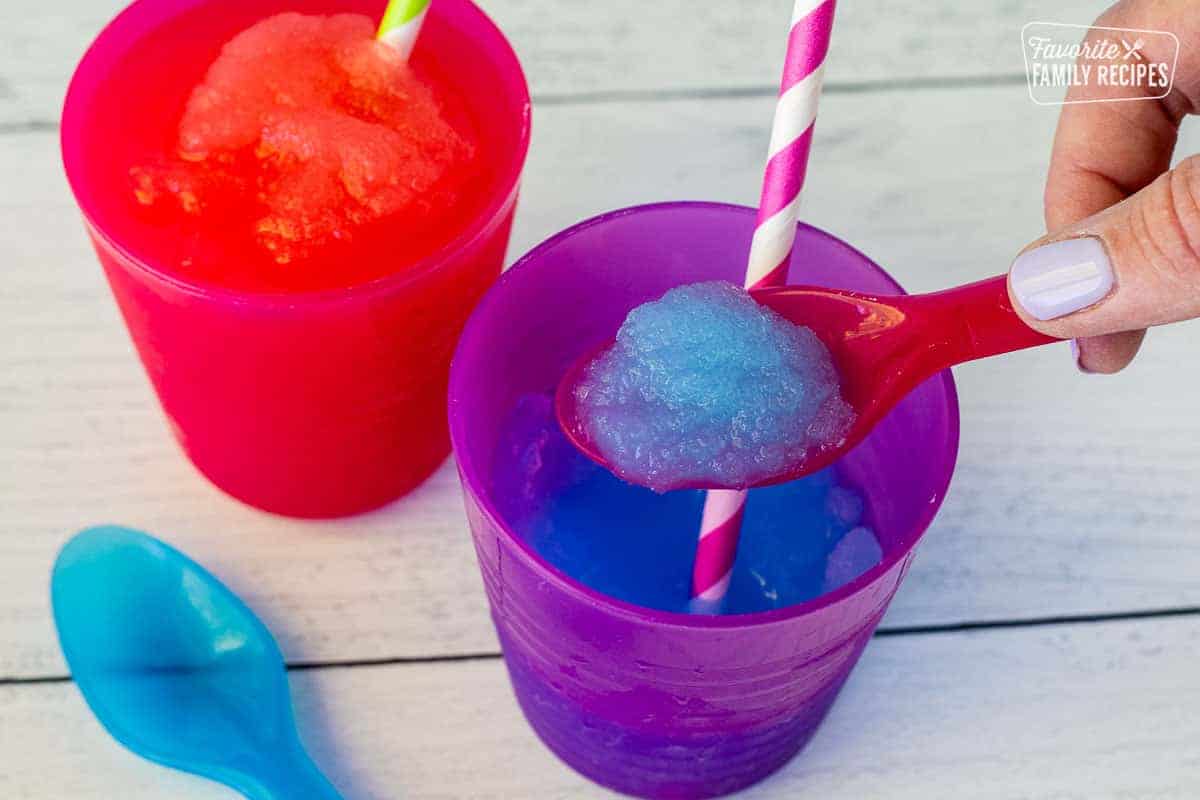 Hand holding up a spoon full of blue slushie in a spoon.