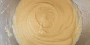 A metal mixing bowl filled with smooth and creamy batter, slightly swirled in the middle. The batter has a light beige color and appears thick and well-mixed.