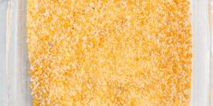 A close-up view of a rectangular glass baking dish filled with a golden-brown crumbly casserole. The dish shows a textured, crispy topping, suggesting it is freshly baked. The background is a neutral-colored surface.
