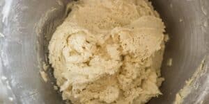 A close-up view of a metal mixing bowl filled with a thick, creamy, and slightly textured dough mixture, likely for baking purposes. The dough appears well combined and ready for the next step in the baking process.