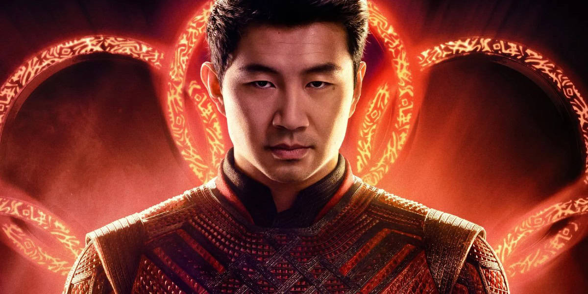 A person wearing ornate red and black clothing stands in front of a glowing red circle with intricate symbols. They have short black hair and a focused expression, set against an abstract, fiery background.