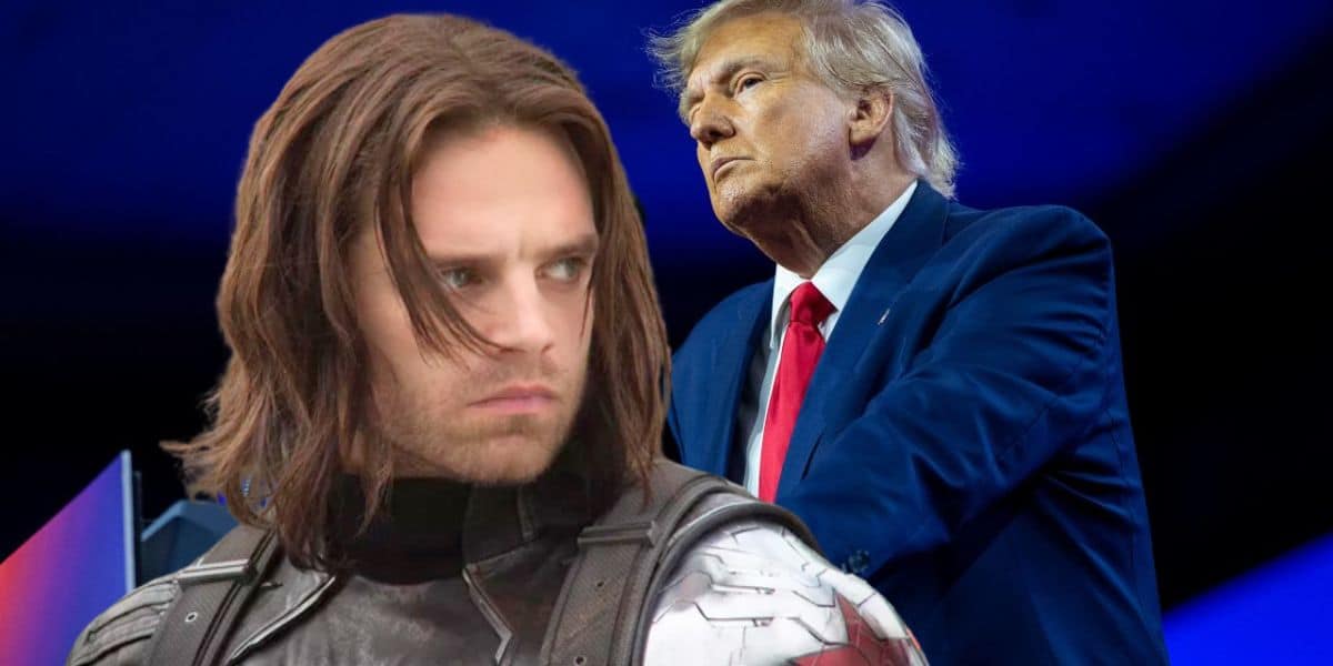 A person in a superhero costume with long hair appears in the foreground, while another person in a suit stands at a podium in the background against a blue backdrop.