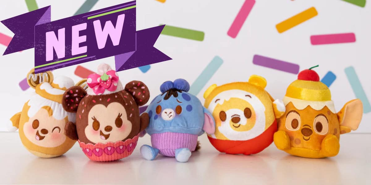 A group of five colorful plush toys with various animal and dessert themes are lined up in front of a white background with multicolored confetti shapes. A purple banner above them reads "NEW" in bold letters.
