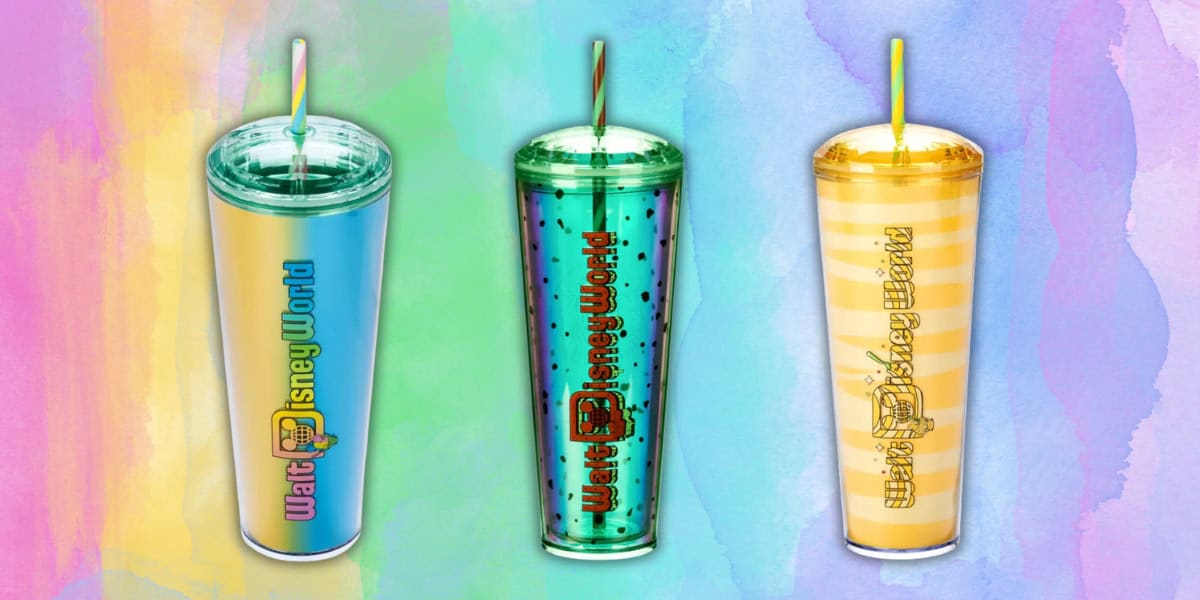 Three colorful Disney World branded tumblers with straws. The first tumbler is pale blue, the second is green with polka dots, and the third is yellow with horizontal stripes. The background features a rainbow watercolor texture.