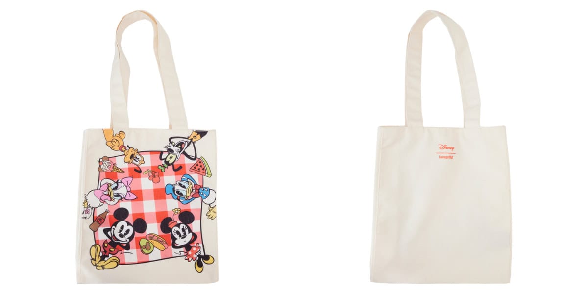 Front and back view of a tote bag. The front features cartoon characters enjoying a picnic with watermelon and sandwiches. The back is plain with a small logo. The bag has long handles and a cream color.
