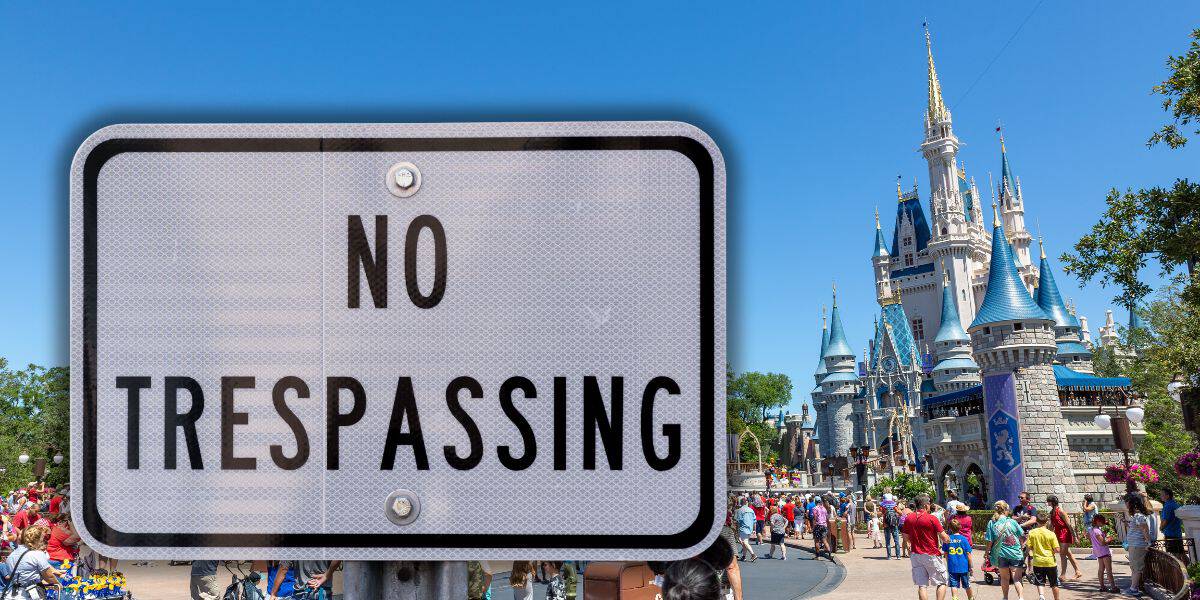 A "No Trespassing" sign in the foreground, with a castle in the background under a clear blue sky. People are walking around in the area near the castle at Magic Kingdom inside Disney World.