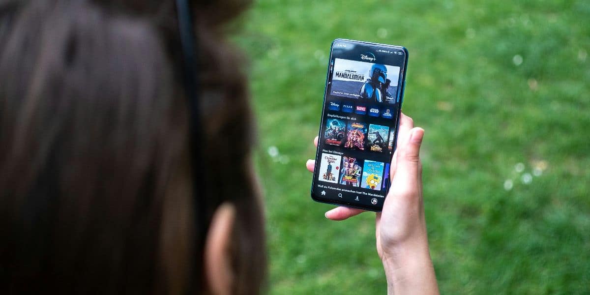 Person holding a smartphone displaying the Disney+ home page