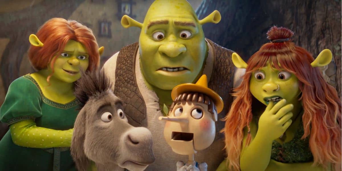 Animated scene featuring green ogres and a talking donkey. A wooden puppet with a long nose stands in the middle. The characters display a range of surprised and inquisitive expressions amid a rustic, woodland background.
