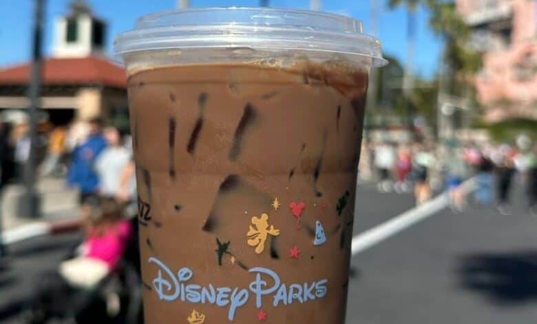 A close-up of a coffee from a Disney Starbucks location in front of the Twilight Zone Tower of Terror.