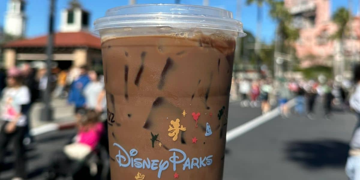 A close-up of a coffee from a Disney Starbucks location in front of the Twilight Zone Tower of Terror.