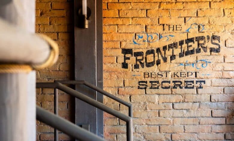 Magic Kingdom brick wall reads "the frontier's best kept secret" in frontierland