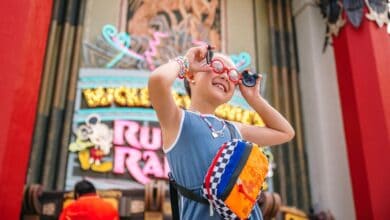 A young girl smiles in front of Mickey & Minnie's Runaway Railway at Disney's Hollywood Studios