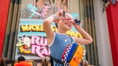 A young girl smiles in front of Mickey & Minnie's Runaway Railway at Disney's Hollywood Studios
