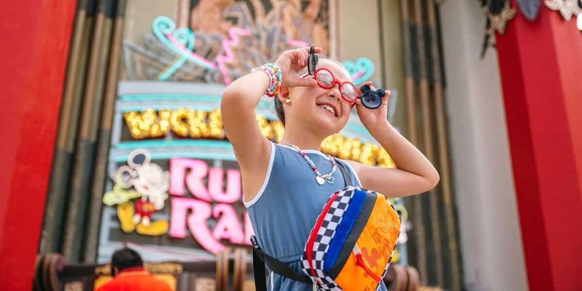 A young girl smiles in front of Mickey & Minnie's Runaway Railway at Disney's Hollywood Studios