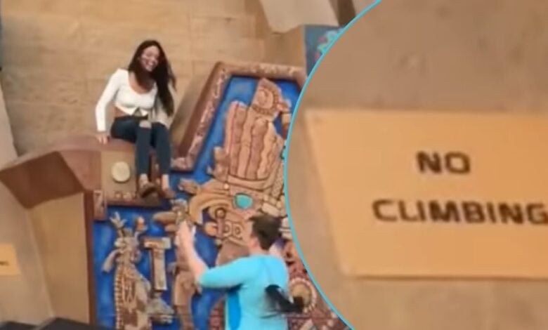 A woman sitting on the EPCOT World Showcase Mexico Pavilion pyramid right next to a "no climbing" sign.