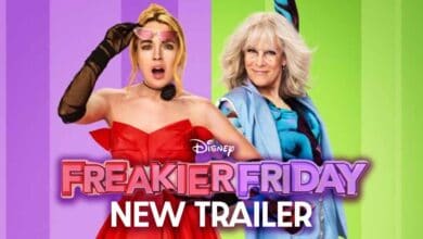 Two women stand in front of colorful green and purple stripes. One wears a red dress and looks surprised with a sleep mask on her head, the other wears glasses and a blue outfit, smiling confidently. Text: “Disney Freakier Friday NEW TRAILER.”.
