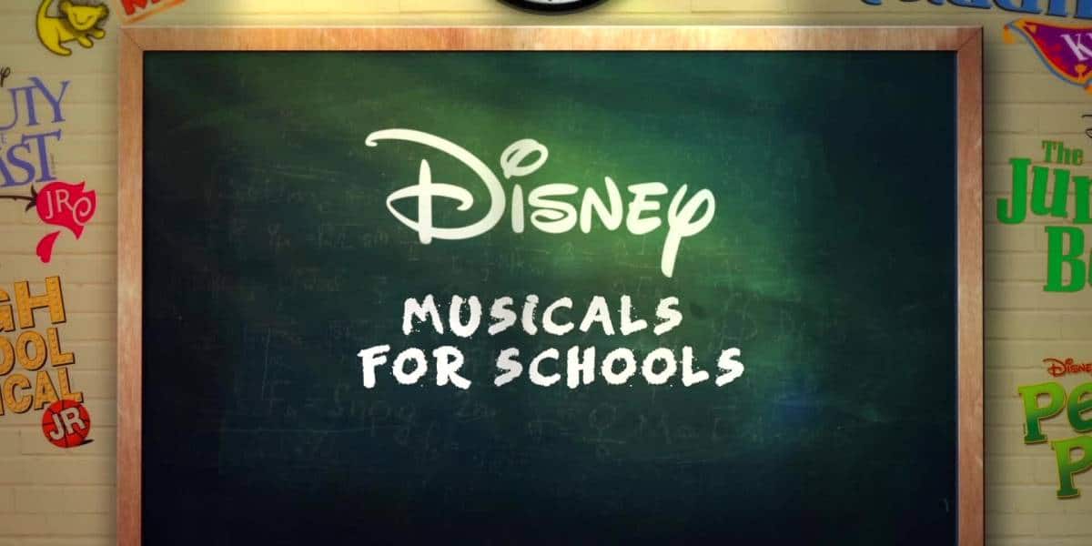 A chalkboard with “Disney Musicals for Schools” written on it in white, surrounded by colorful posters of Disney Musicals in Schools on a yellow brick wall.