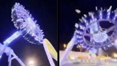 A brightly lit amusement park ride spins at night, with people seated around its circular edge. Elevated high above the ground and illuminated by blue and white lights, it captures the thrill—and risks—often discussed after theme park accidents.