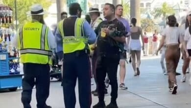 Disneyland Resort security talks to a man holding a drink at Disney California Adventure Park.