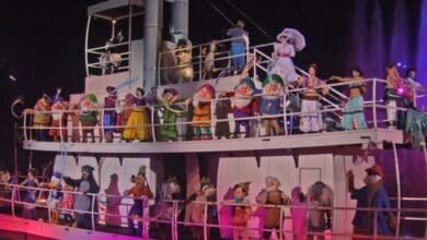 A large group of Disney characters on a boat in the finale of Fantasmic!