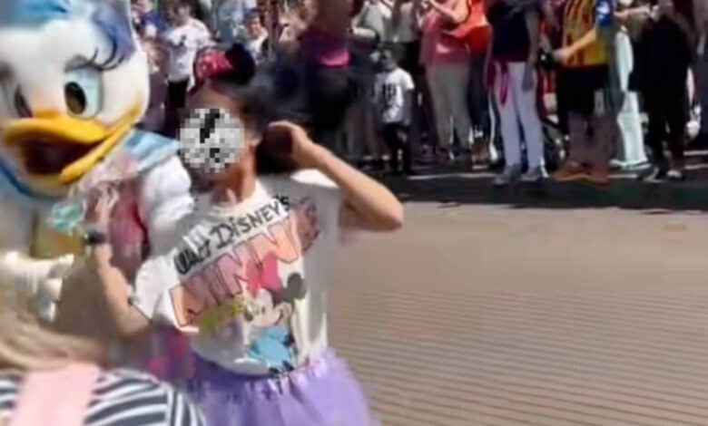 Daisy Duck escorts a child who walked into a moving Disney parade.