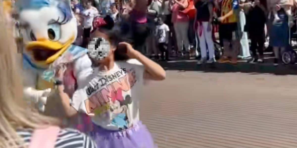 Daisy Duck escorts a child who walked into a moving Disney parade.