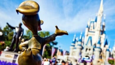 A close-up of a bronze Donald Duck statue in front of Cinderella Castle at Magic Kingdom.