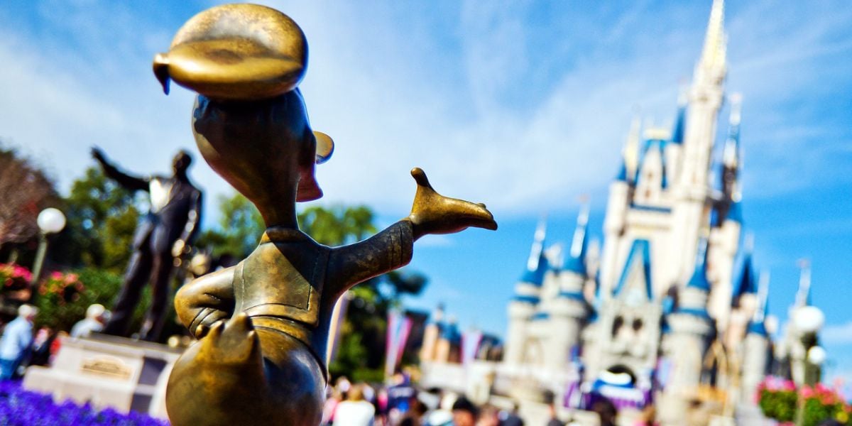 A close-up of a bronze Donald Duck statue in front of Cinderella Castle at Magic Kingdom.