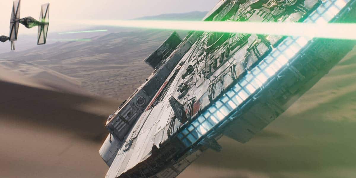 The Millennium Falcon flies at an angle over a desert landscape, evading green laser fire from TIE fighters pursuing it in the background—a scene worthy of trailers that broke the internet.