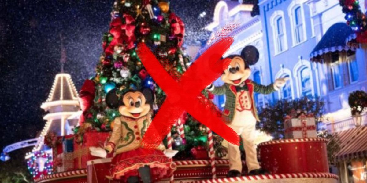 Two people in festive costumes pose by a decorated Christmas tree and parade float at night; buildings are adorned with lights. A large red "X" is drawn over the center of the image.