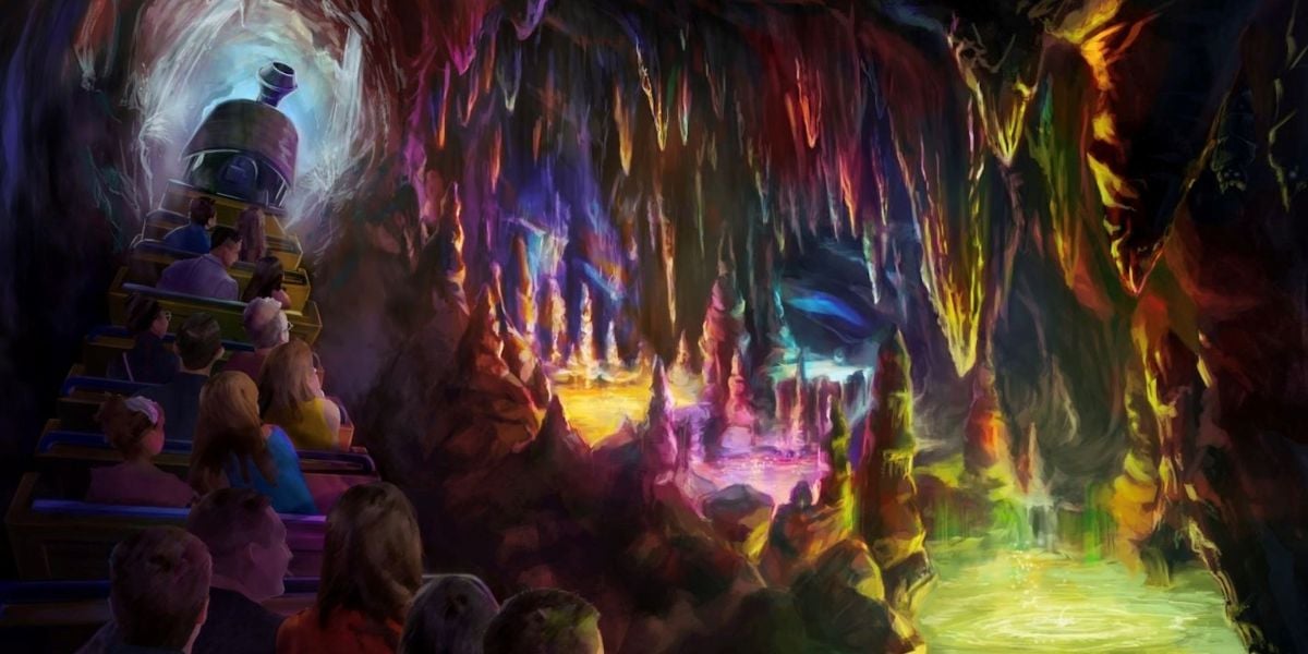 A group of people ride a train through a colorful, glowing cave filled with vibrant stalactites and stalagmites illuminated in shades of purple, orange, yellow, and green.