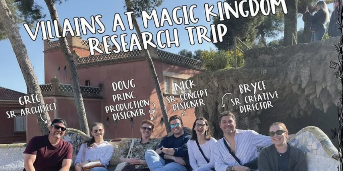A group of eight people sits and smiles outdoors on a sunny day in front of a pink building. Above them, handwritten text labels each person’s name and creative role related to a "Magic Kingdom Villains" research trip.