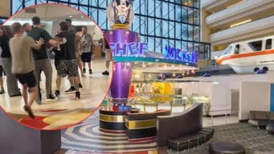A group of men appear to argue in a hotel lobby, shown in a red circle overlay. Behind, the spacious modern lobby features Chef Mickey’s restaurant and a monorail passing through the Contemporary Resort.
