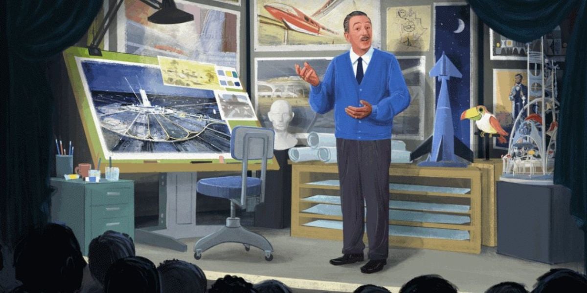 A man in a blue cardigan stands onstage in front of sketches, models, and a drafting desk, giving a presentation to an audience. Spacecraft models and artwork are displayed behind him.
