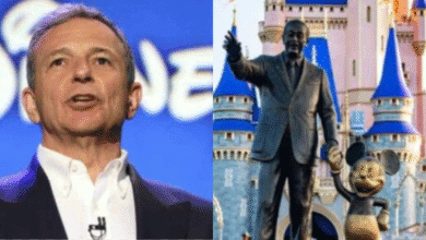 A man in a suit stands in front of a Disney logo on the left; on the right, a statue of Walt Disney holding hands with Mickey Mouse stands in front of a Disney castle.