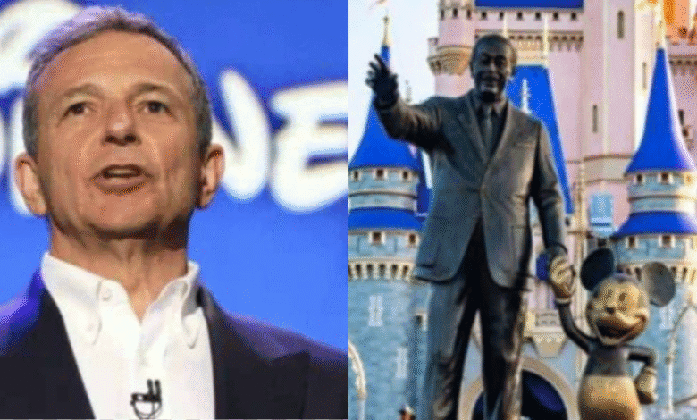 A man in a suit stands in front of a Disney logo on the left; on the right, a statue of Walt Disney holding hands with Mickey Mouse stands in front of a Disney castle.
