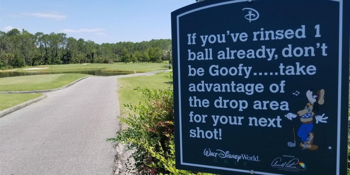 A sign at a Disney World golf course reads, "If you’ve rinsed 1 ball already, don’t be Goofy… take advantage of the drop area for your next shot!" with Goofy pictured near the golf cart path and lush green landscape.