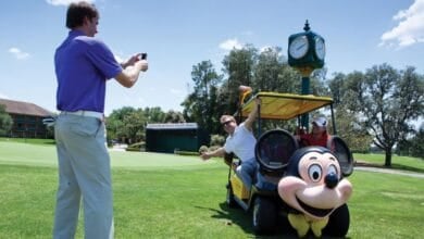 Two people posing near a Mickey Mouse golf cart at Walt Disney World Resort
